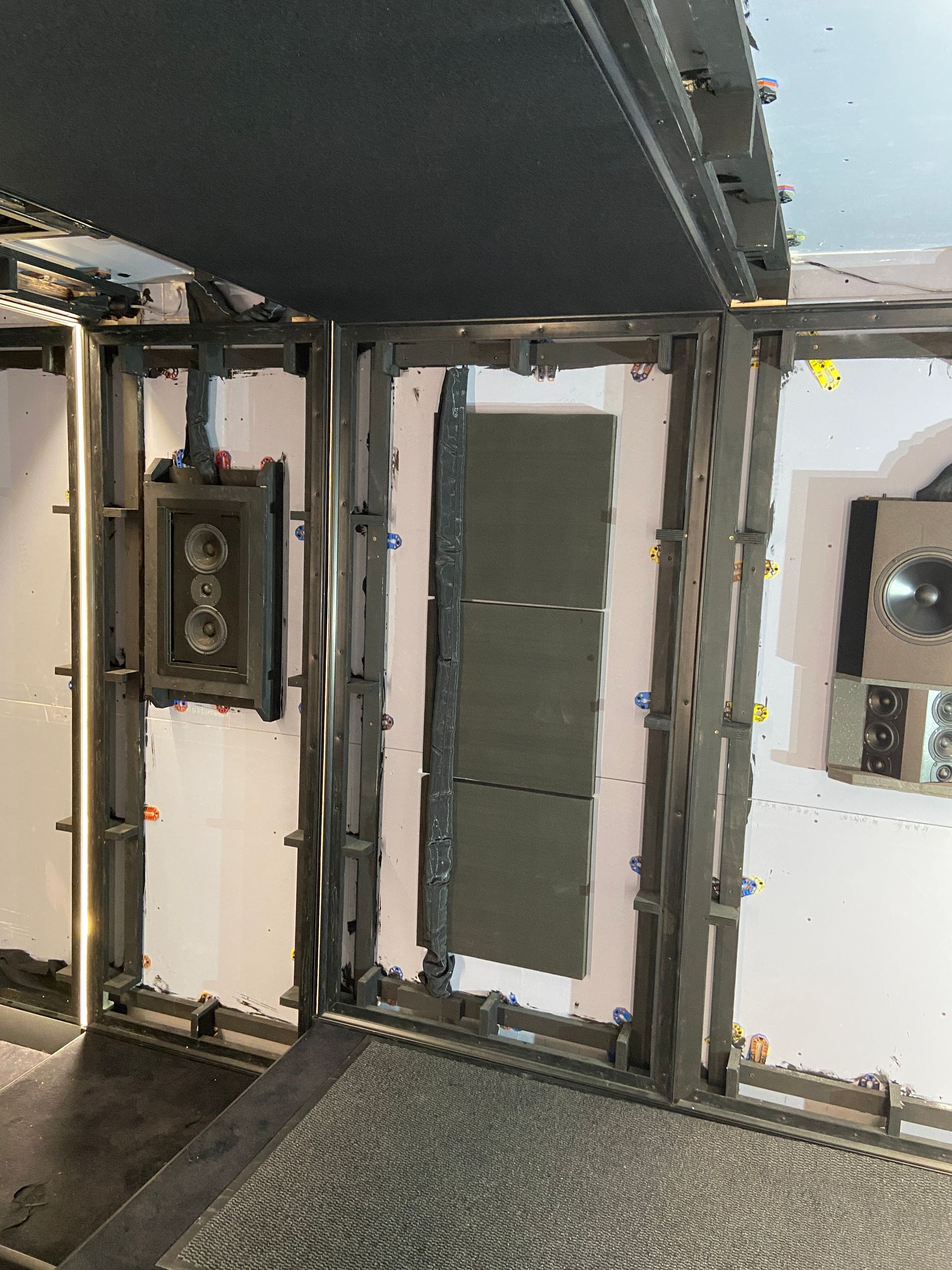 Interior view of a rectangular sound-dampening room with metal frame, acoustic panels, and a speaker system.