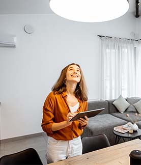 Lady looking up at light on ceiling while holding an ipad tablet computer