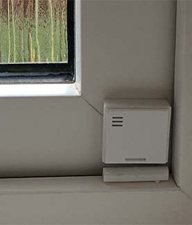 A photograph of a window contact sensor on a window frame of a closed window