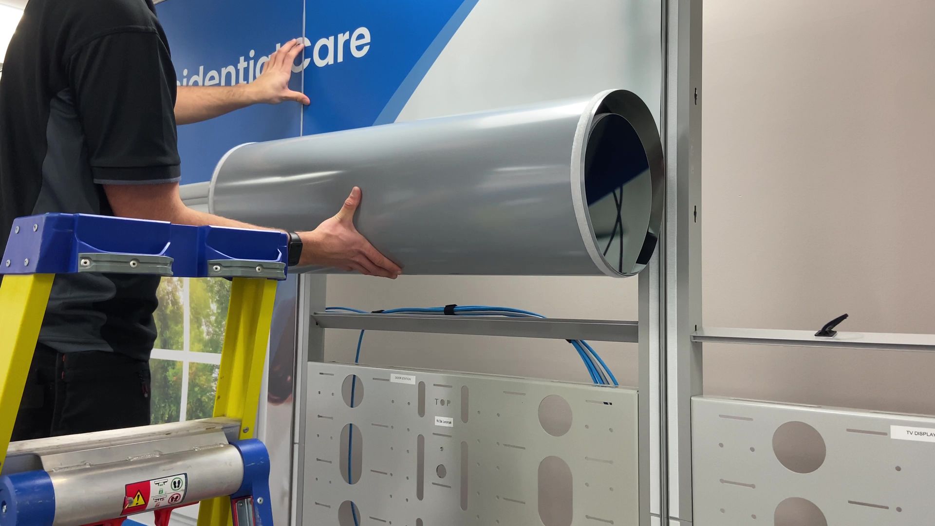 Photograph of attaching the vinyl printed graphics onto the exhibition space display system panels