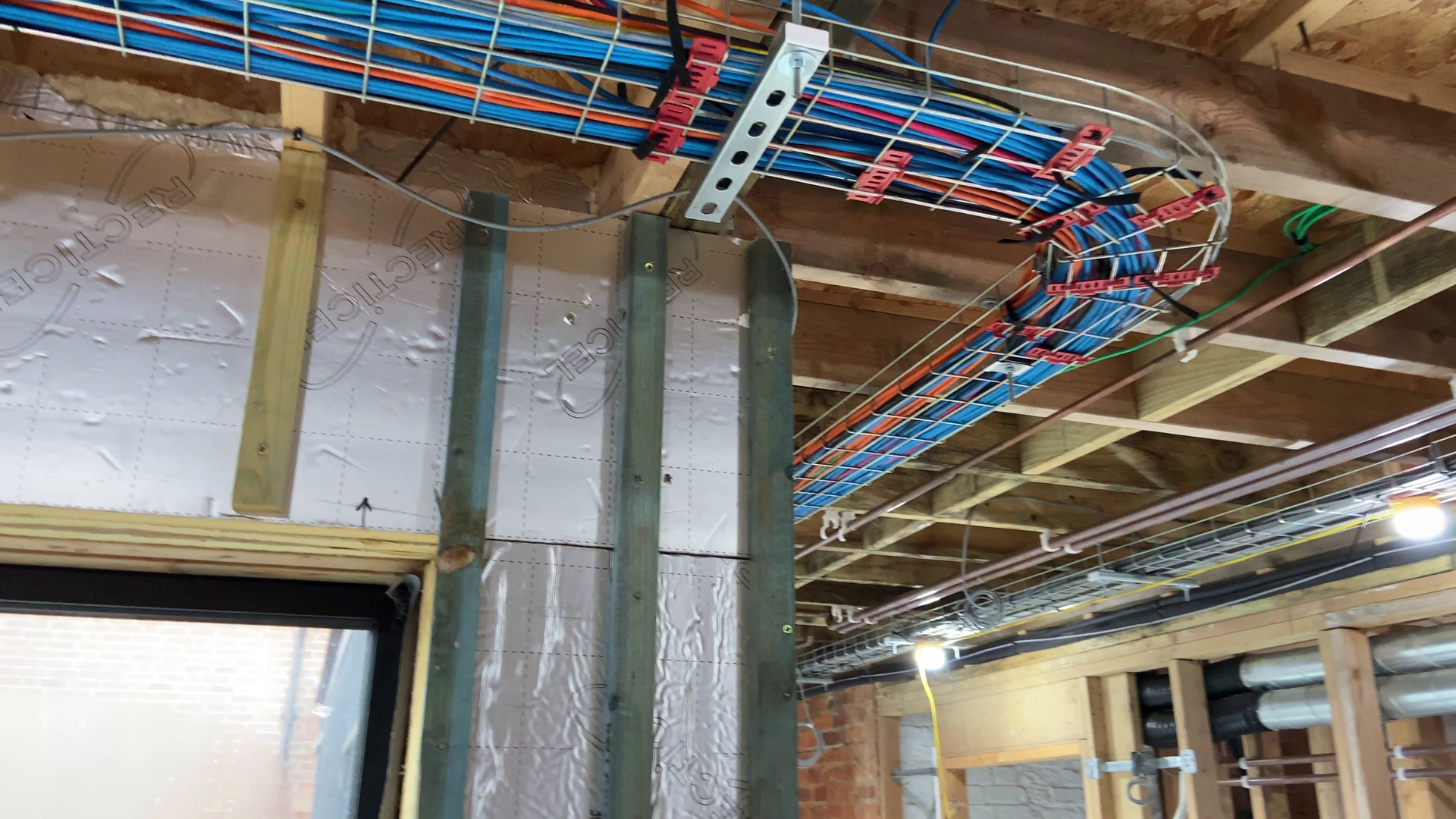Photo of Metal basket tray in the ceiling of hall with a variety of cables inside it