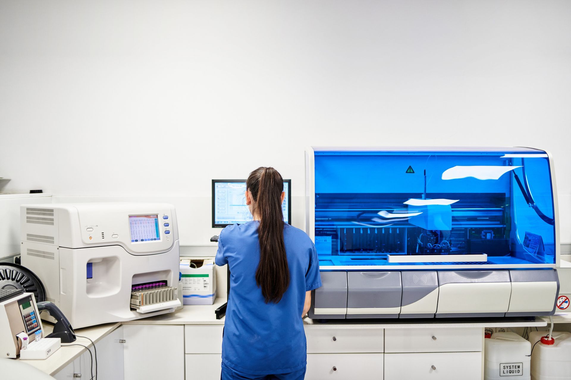 A worker is using a computer while working in a clinical analysis laboratory.