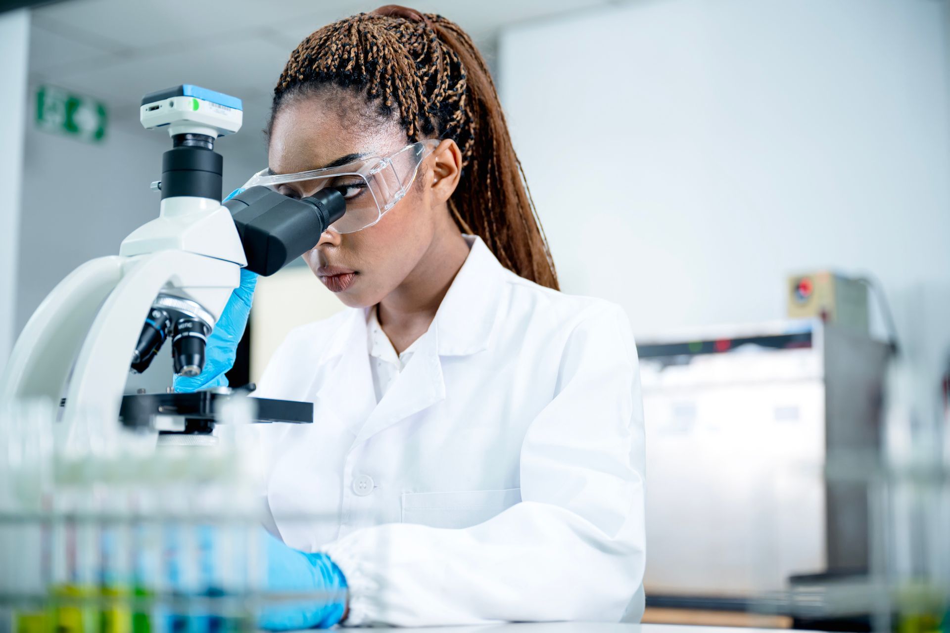 A woman scientist is conducting research on a scientific sample through a microscope. A woman scientist is conducting research on a scientific sample through a microscope.