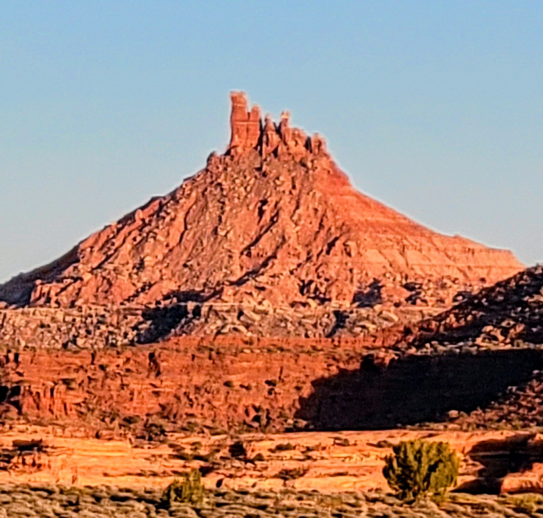 A mountain in the desert with a blue sky in the background