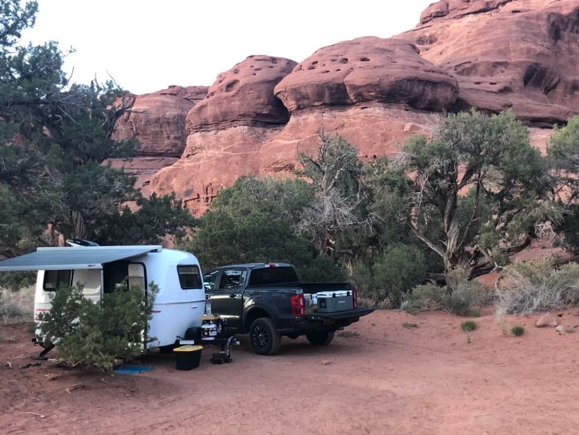 A camper is parked under a canopy in the desert.