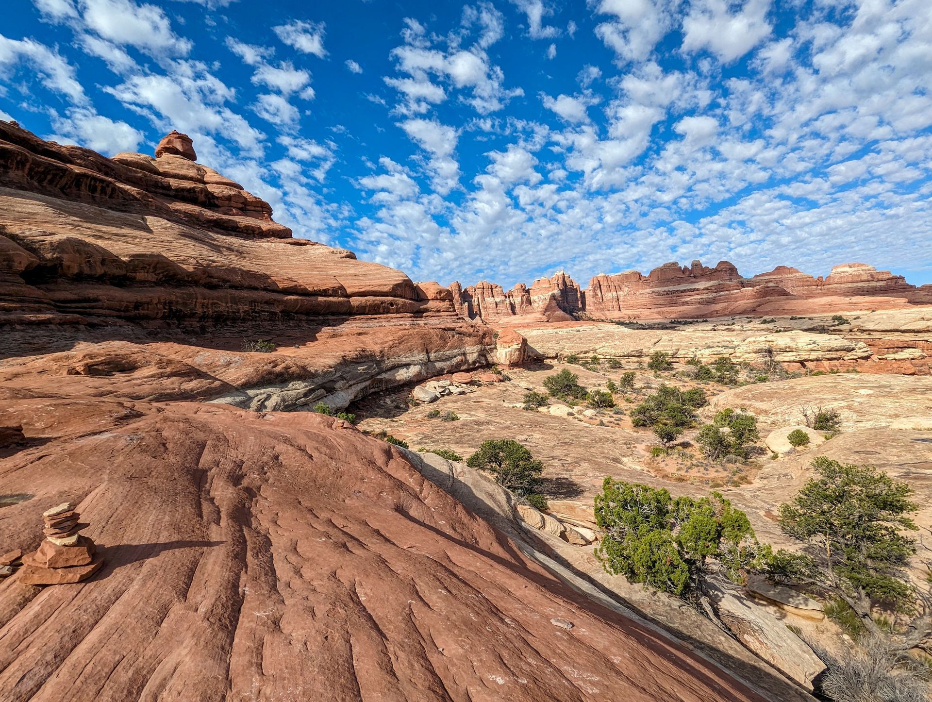 A desert landscape with mountains in the background and a blue sky with clouds