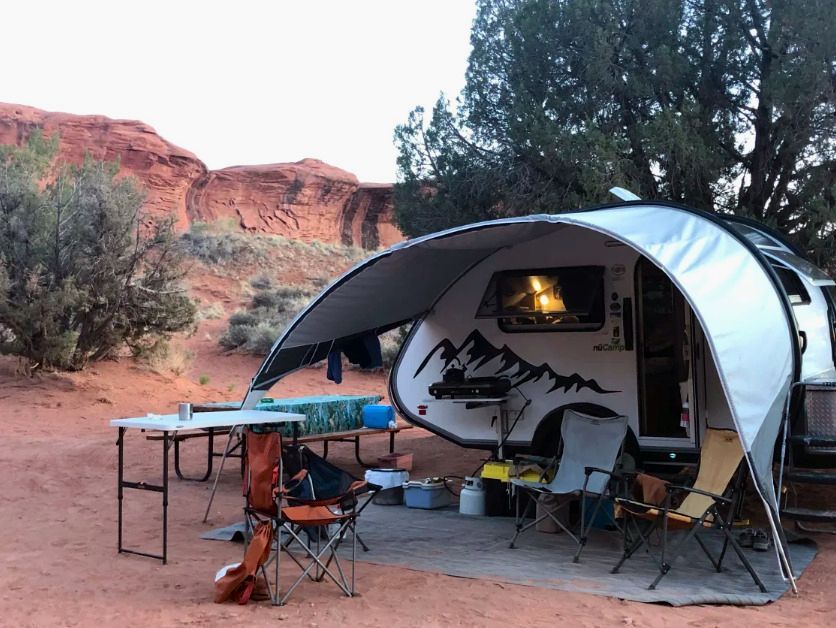 A camper is parked under a canopy in the desert.