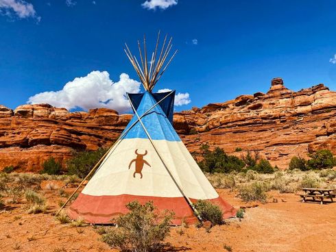 A teepee is sitting in the middle of a desert.