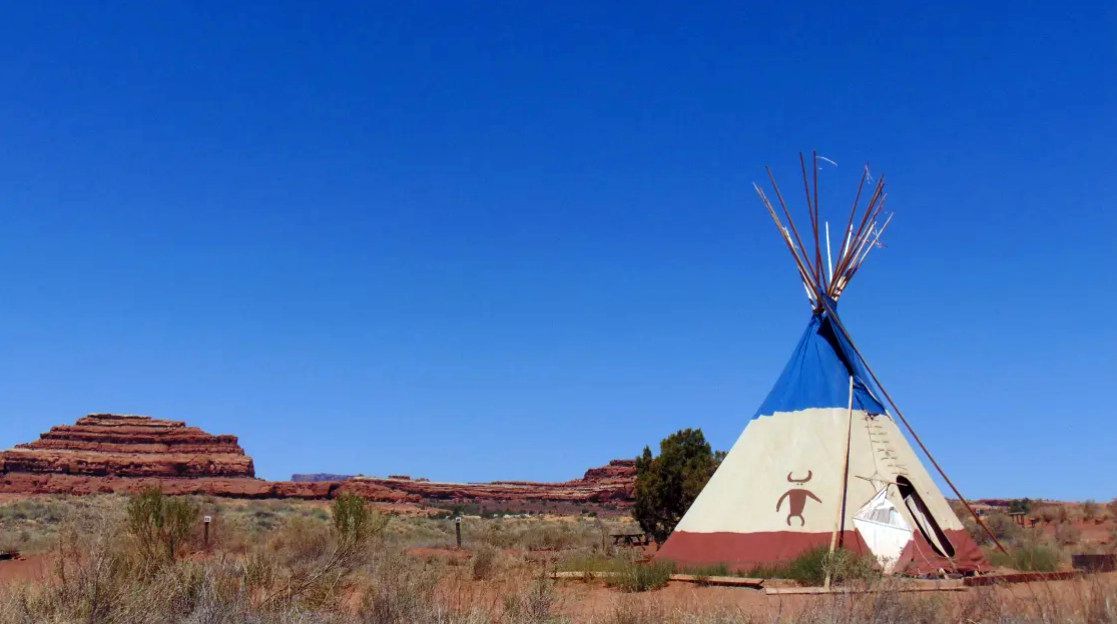 A teepee is sitting in the middle of a desert.