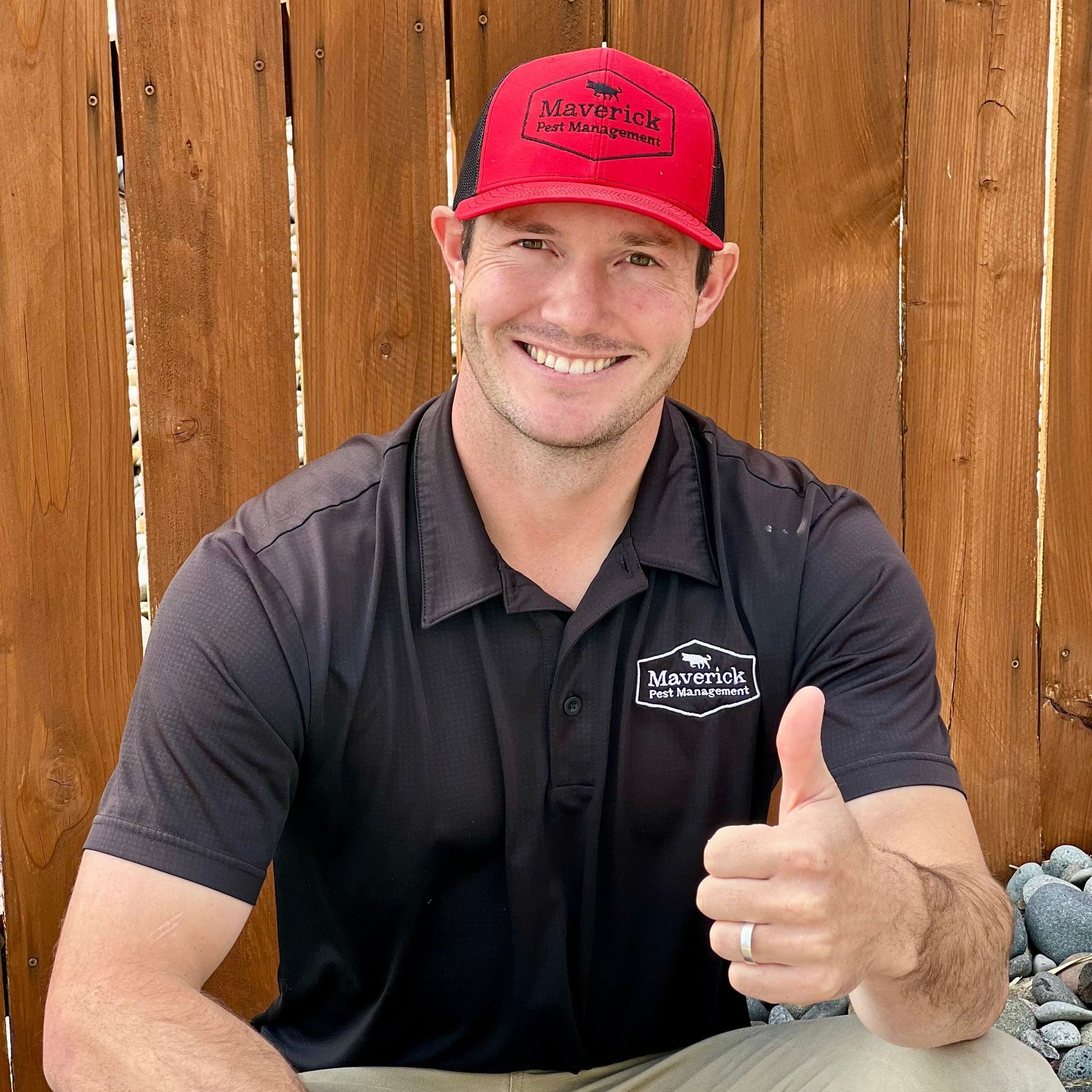 a man wearing a maverick pest management shirt gives a thumbs up