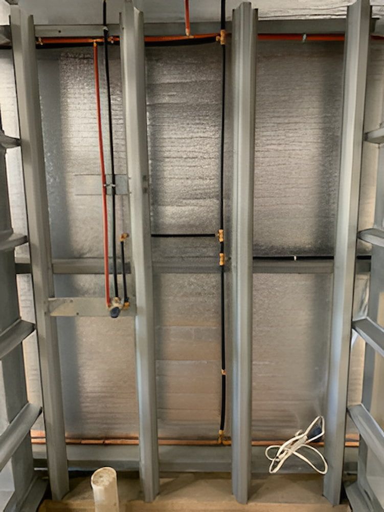 A Room With A Lot Of Pipes Hanging From The Ceiling — DAVMAC Plumbing in Wauchope, NSW
