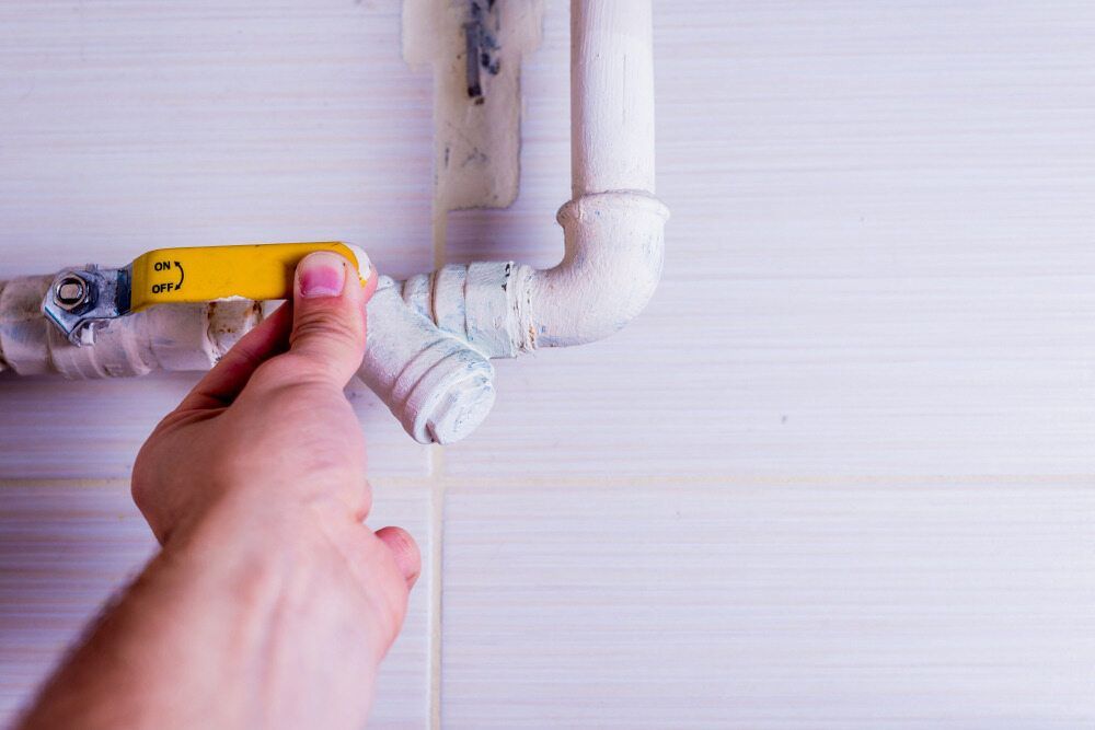 A Person Is Fixing A Pipe With A Yellow Valve — DAVMAC Plumbing in Wauchope, NSW