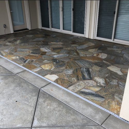 Stone patio with concrete border next to sliding glass doors.