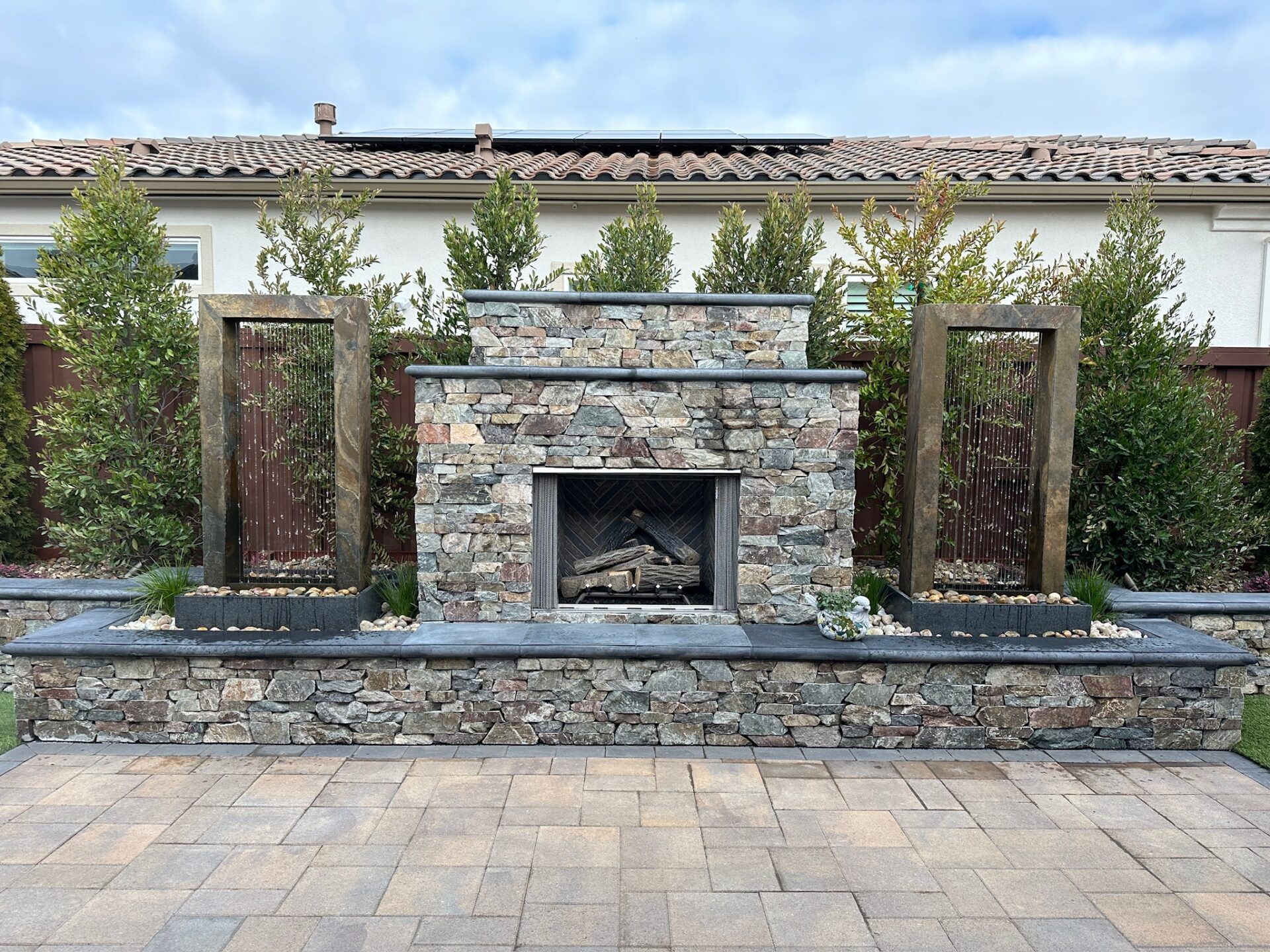 Outdoor stone fireplace with water features flanking it.