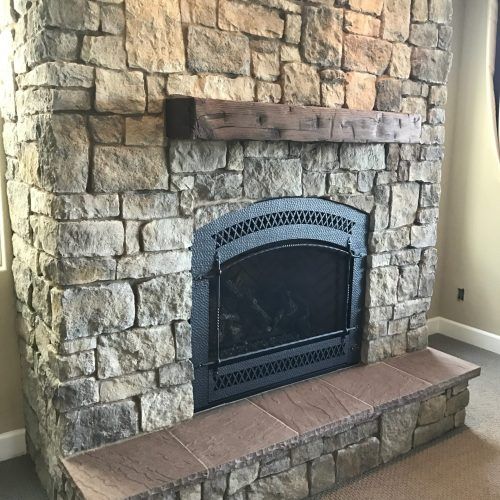 Stone fireplace with dark metal firebox and wooden mantle.