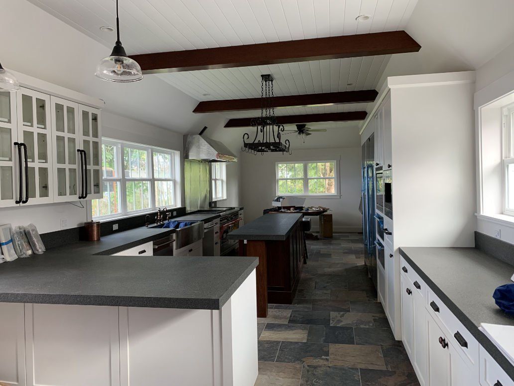 A kitchen with white cabinets and black counter tops