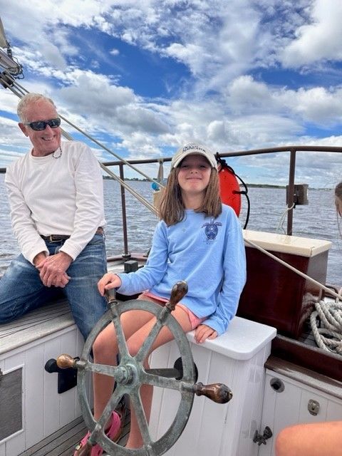 A little girl is sitting at the steering wheel of a boat