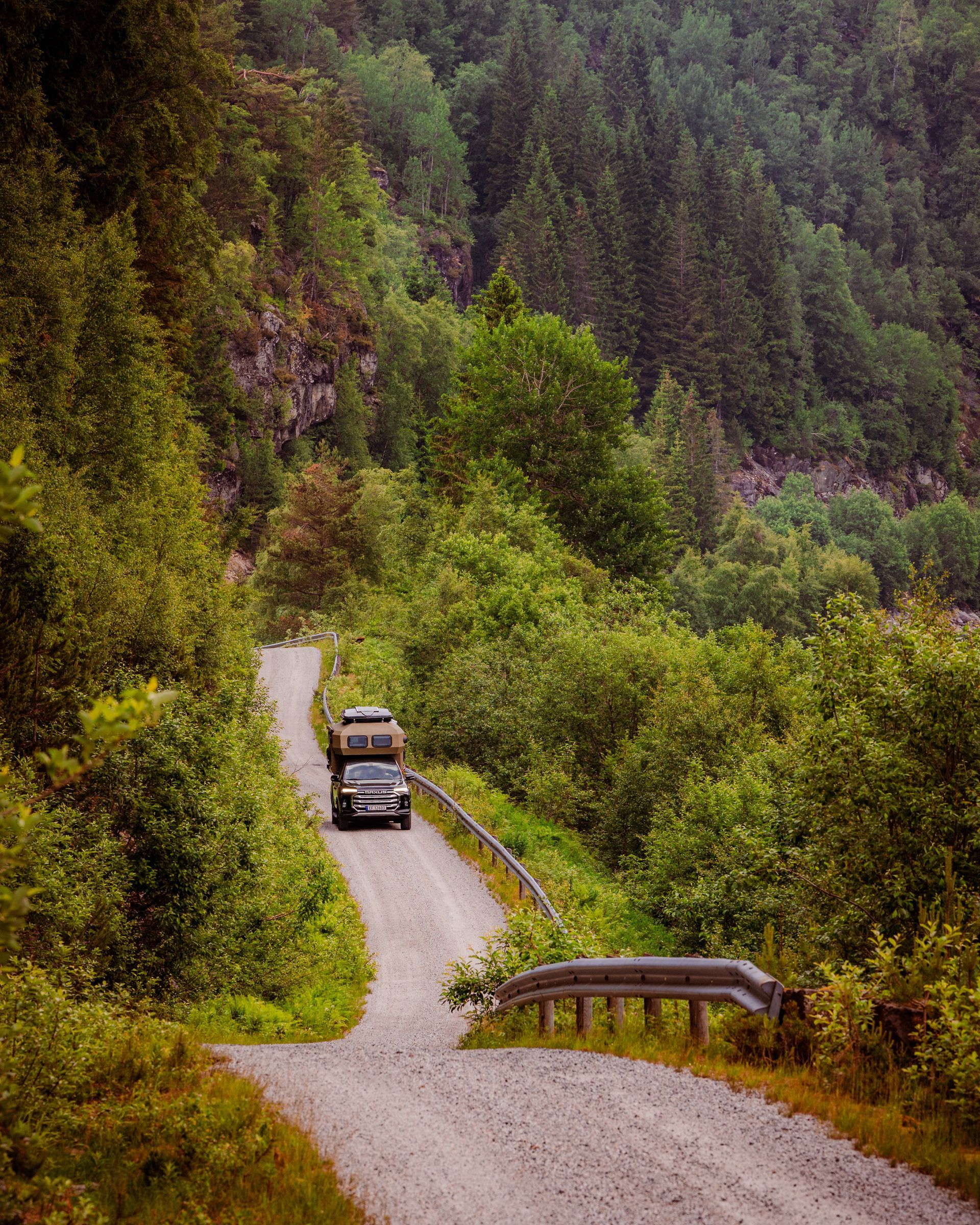 An electric pickup camper from Norway Overland driving on dramatic Norwegian road.