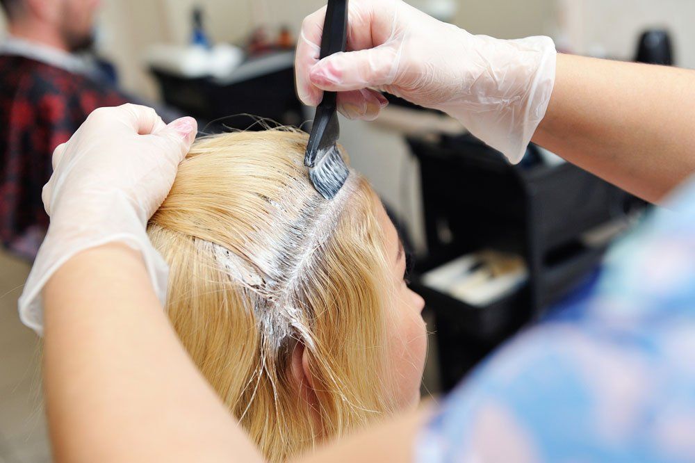 Hairdresser Applying Dye On Woman Hair At Salon