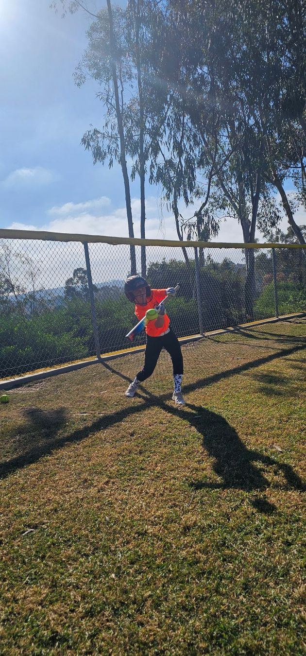 Baseball glove with ball on green grass, with blurred baseballs in the background.