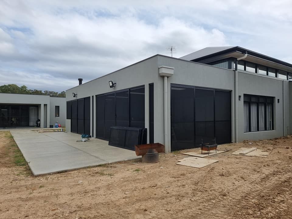 A large house with a lot of windows is sitting on top of a dirt field.