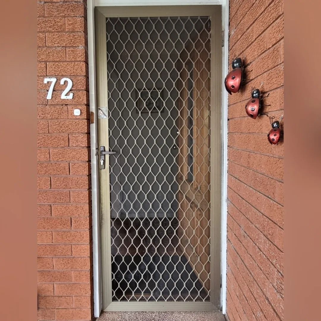 A brick wall with a door and the number 72 on it.