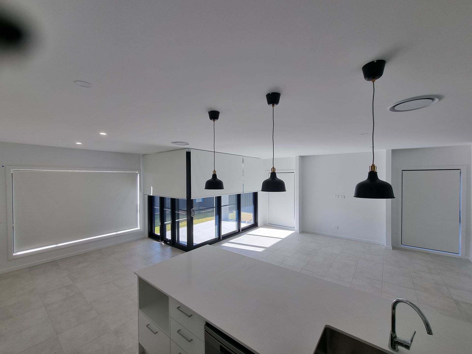 A kitchen with white cabinets and black pendant lights hanging from the ceiling.