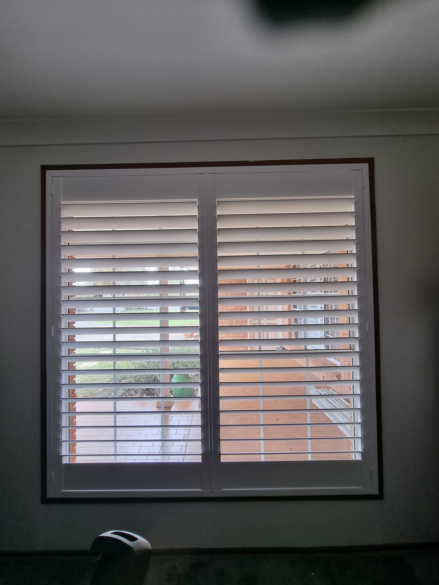 A window with shutters on it and a ceiling fan