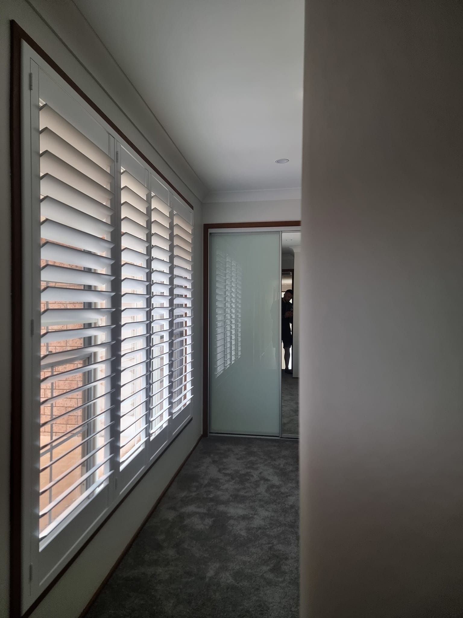 A hallway with shutters on the windows and a sliding glass door