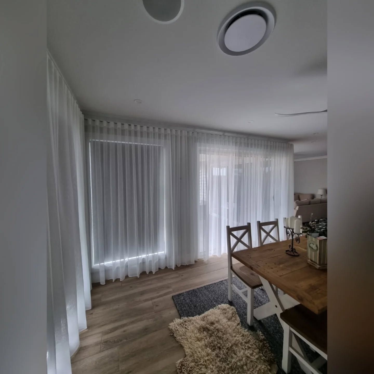 A dining room with a table and chairs and white curtains