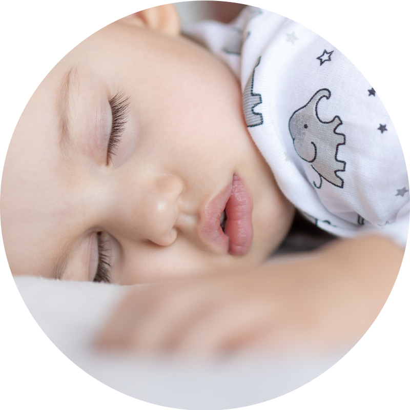 A baby wearing an elephant bib is sleeping.