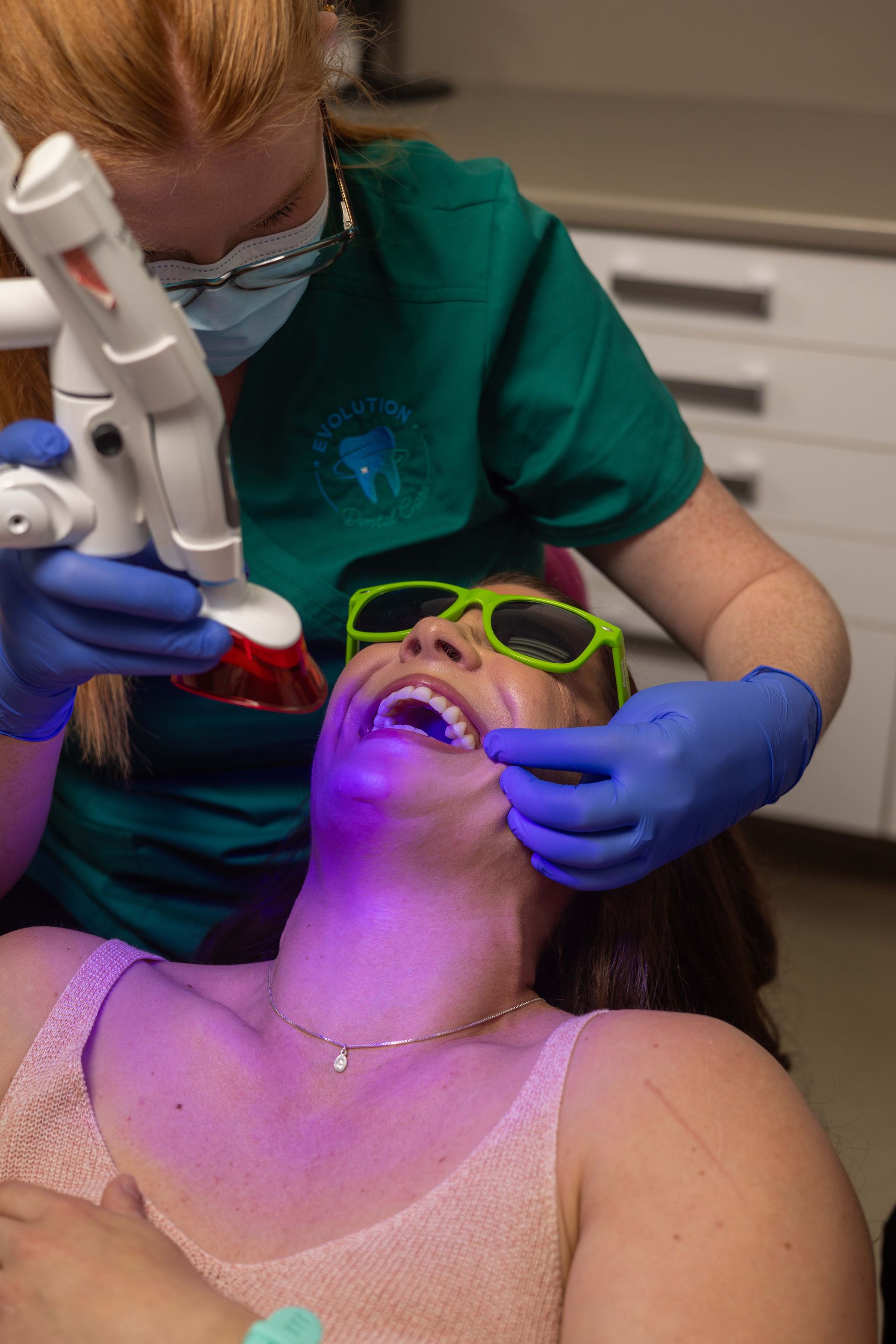 A woman is getting her teeth whitened by a dentist.