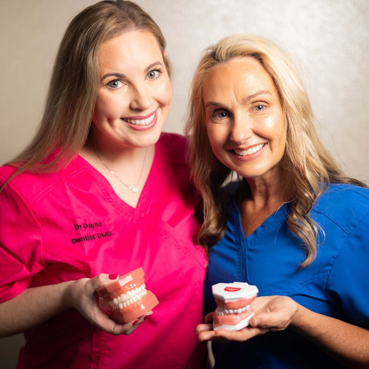 Two women in pink scrubs are posing for a picture together