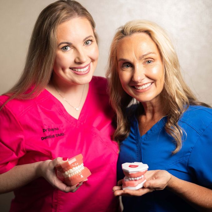 Two women in pink scrubs are posing for a picture together