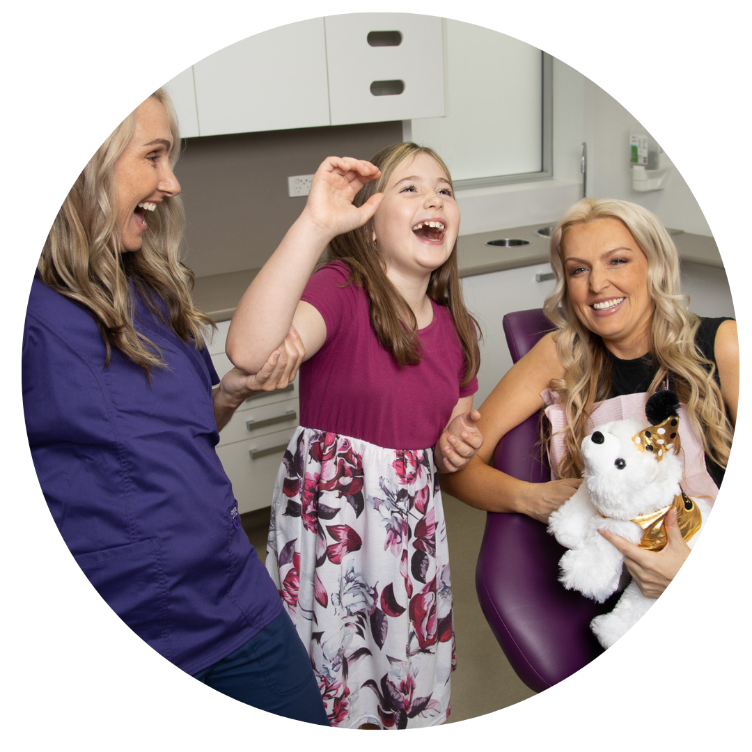 A woman is holding a stuffed animal and a little girl is laughing