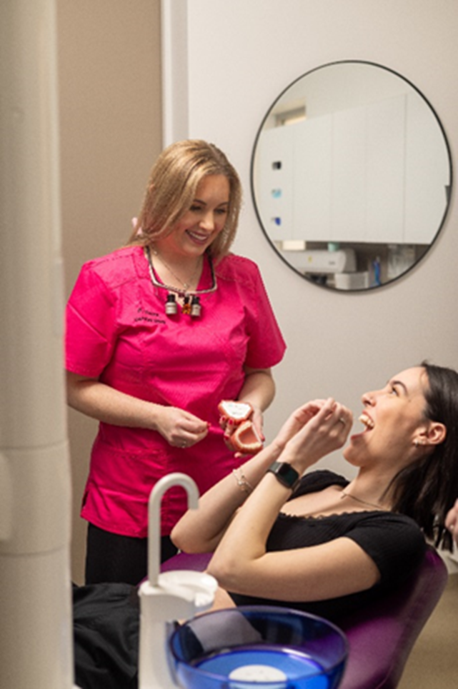 A woman sitting in a dental chair holding a mirror that says pola