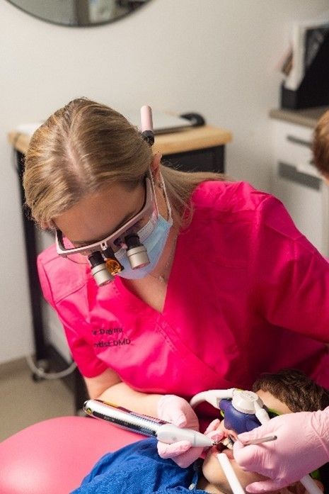 A female dentist is examining a child 's teeth in a dental office.