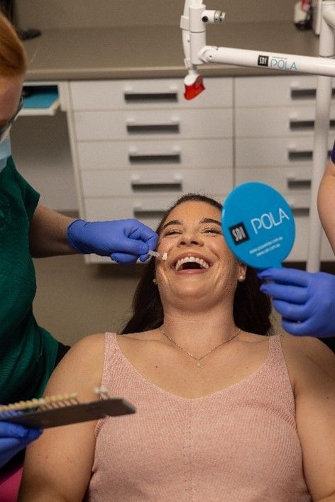A woman is laughing while getting her teeth examined by a dentist