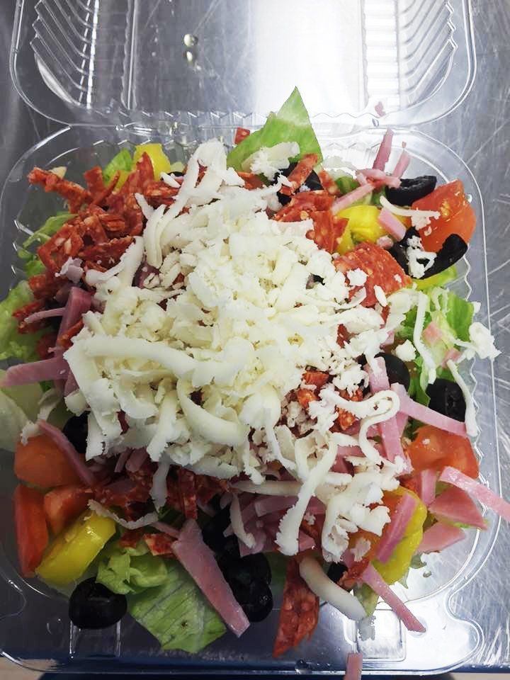 A close up of a salad in a plastic container on a table.