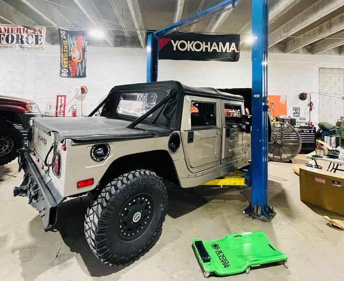 A humvee is sitting on a lift in a garage. | CB Wheels & Tires, 4x4, Suspension, Center