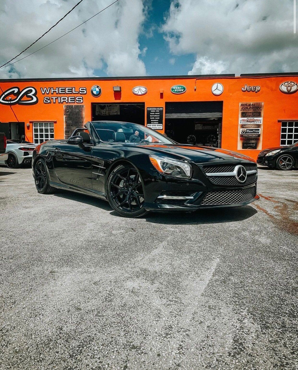 A black sports car is parked in front of an orange building. | CB Wheels & Tires, 4x4, Suspension, Center