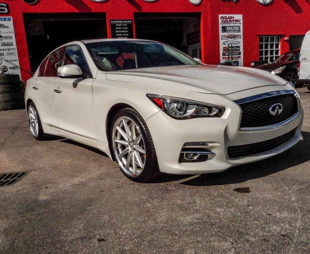 A white car is parked in front of a red building | CB Wheels & Tires, 4x4, Suspension, Center