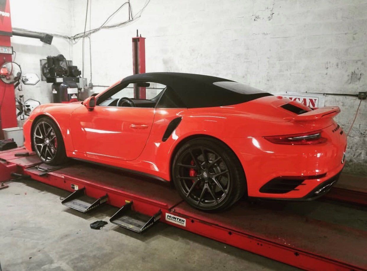 A red sports car is sitting on a lift in a garage. | CB Wheels & Tires, 4x4, Suspension, Center