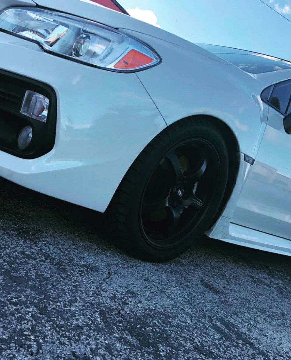 A white car with black wheels is parked on a gravel road. | CB Wheels & Tires, 4x4, Suspension, Center