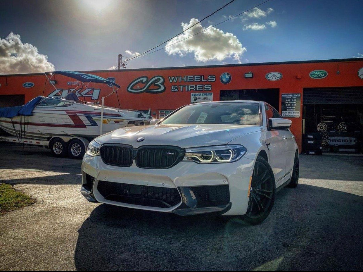 A white bmw m5 is parked in front of a building. | CB Wheels & Tires, 4x4, Suspension, Center