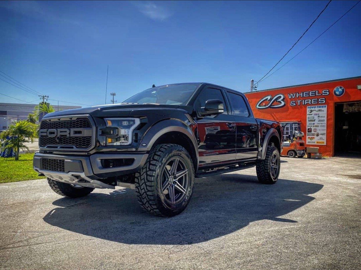 A black ford raptor is parked in front of a tire shop. | CB Wheels & Tires, 4x4, Suspension, Center
