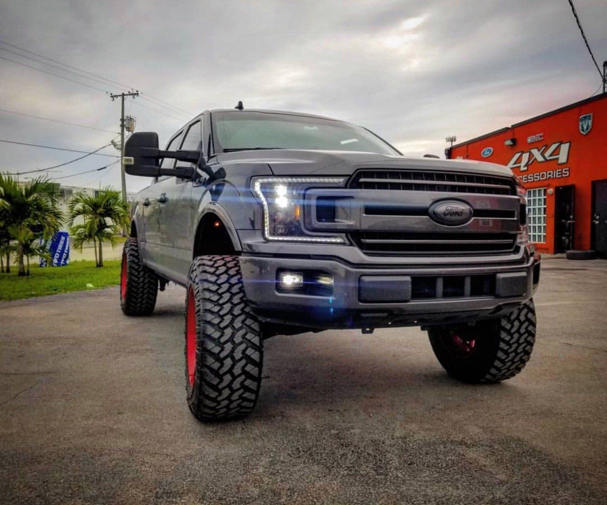 A black truck with red tires is parked in front of a building. | CB Wheels & Tires, 4x4, Suspension, Center