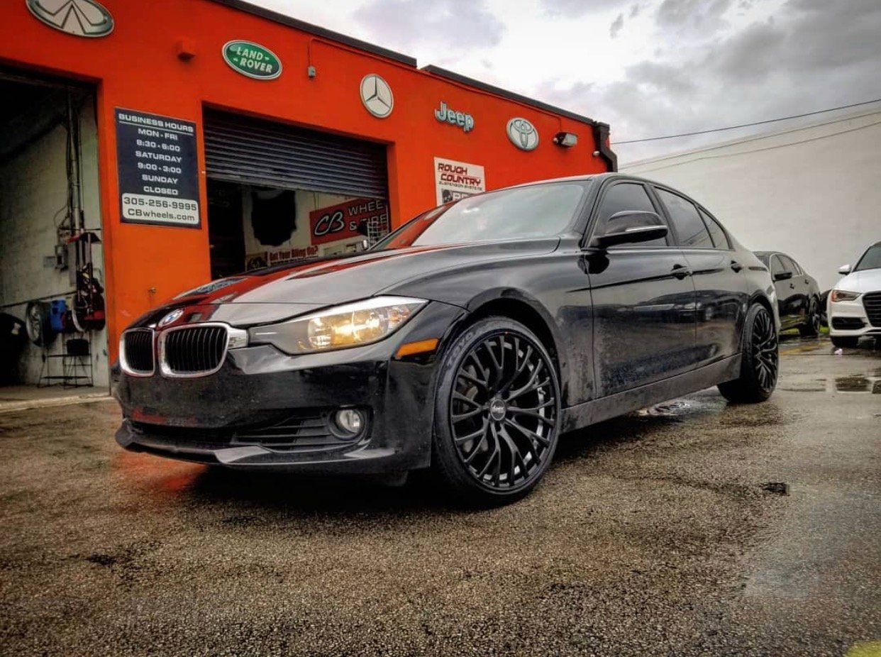 A black car is parked in front of an orange building. | CB Wheels & Tires, 4x4, Suspension, Center