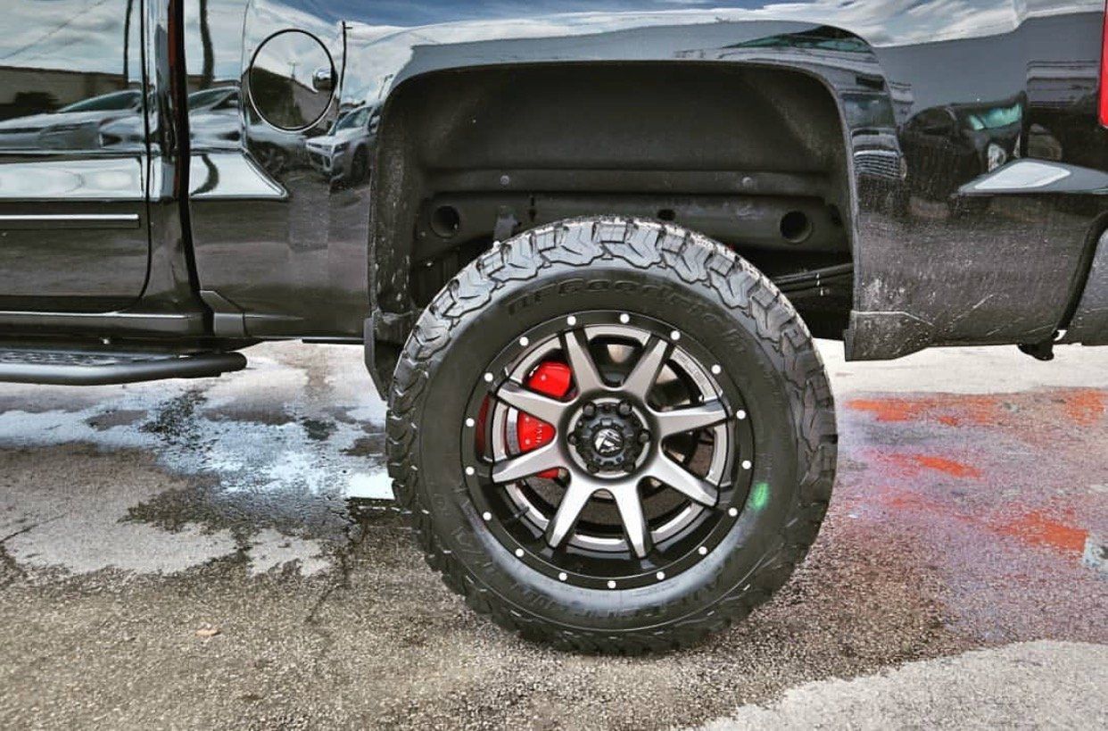 A black truck with red brake calipers and black wheels is parked on the side of the road. | CB Wheels & Tires, 4x4, Suspension, Center