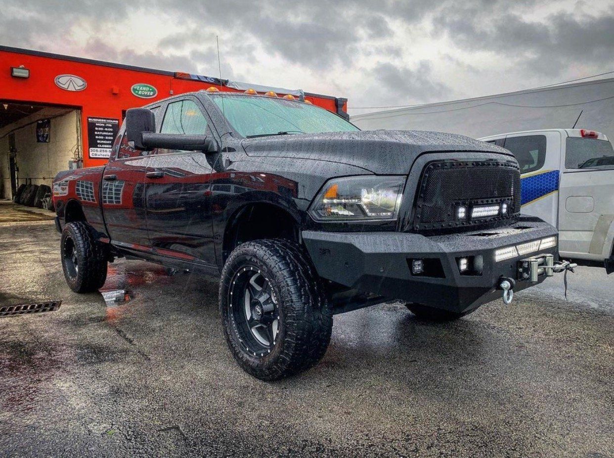 A black dodge ram truck is parked in front of a building. | CB Wheels & Tires, 4x4, Suspension, Center